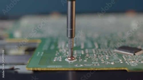 repairman untighten bolt with red thread in sealant to fasten microchip to case. Minor work with microelectronics, board for electrical circuits. Repair of electronic equipment at home or in workshop photo