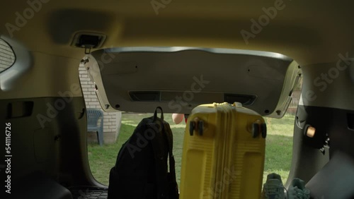 The girl takes the luggage from the trunk. A woman takes out a backpack from a car. A person travels by car. High quality 4k footage