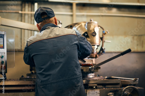 Old milling machine operator works with vintage equipment © nordroden