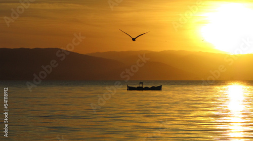 sunset over the sea on the beach with boat and bird flying - Florianópolis, Brazil
