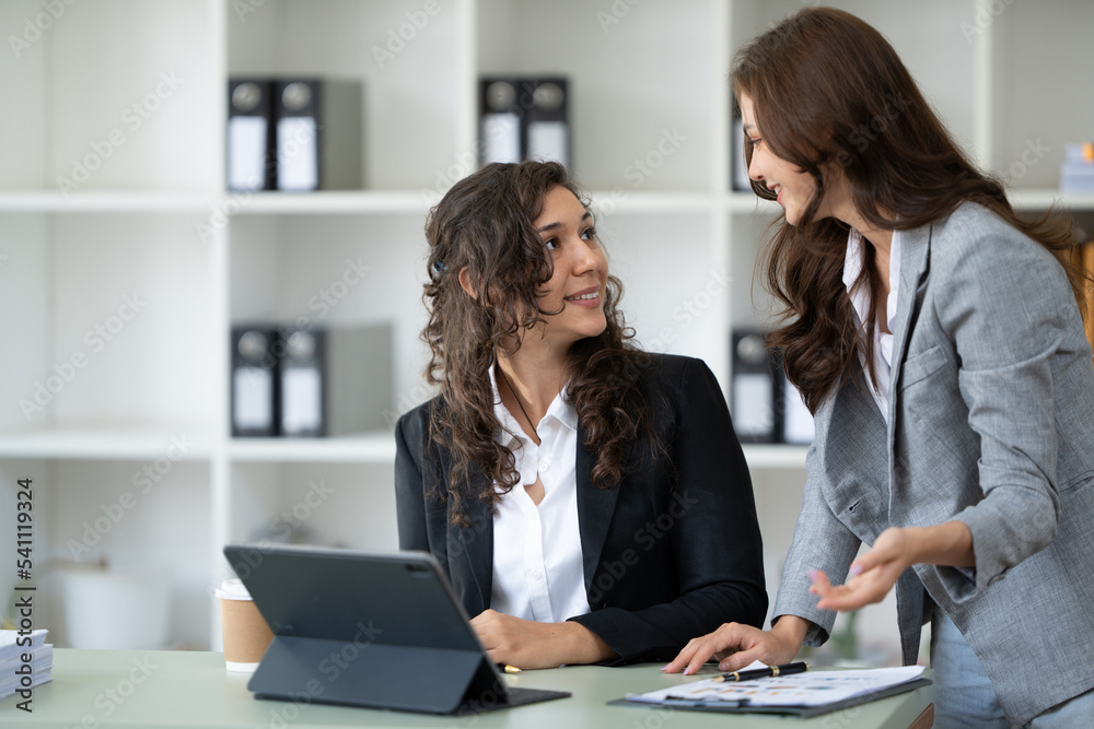Cheerful young female entrepreneur browsing tablet and laptop at workplace in office. Cheerful young female entrepreneur browsing tablet and laptop at workplace in office.
