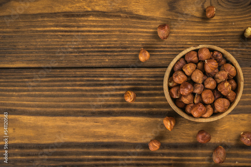 Fresh hazelnuts in a wooden bowl on a wooden background.