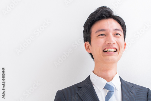 話をする若いスーツを着た日本人男性・白バック