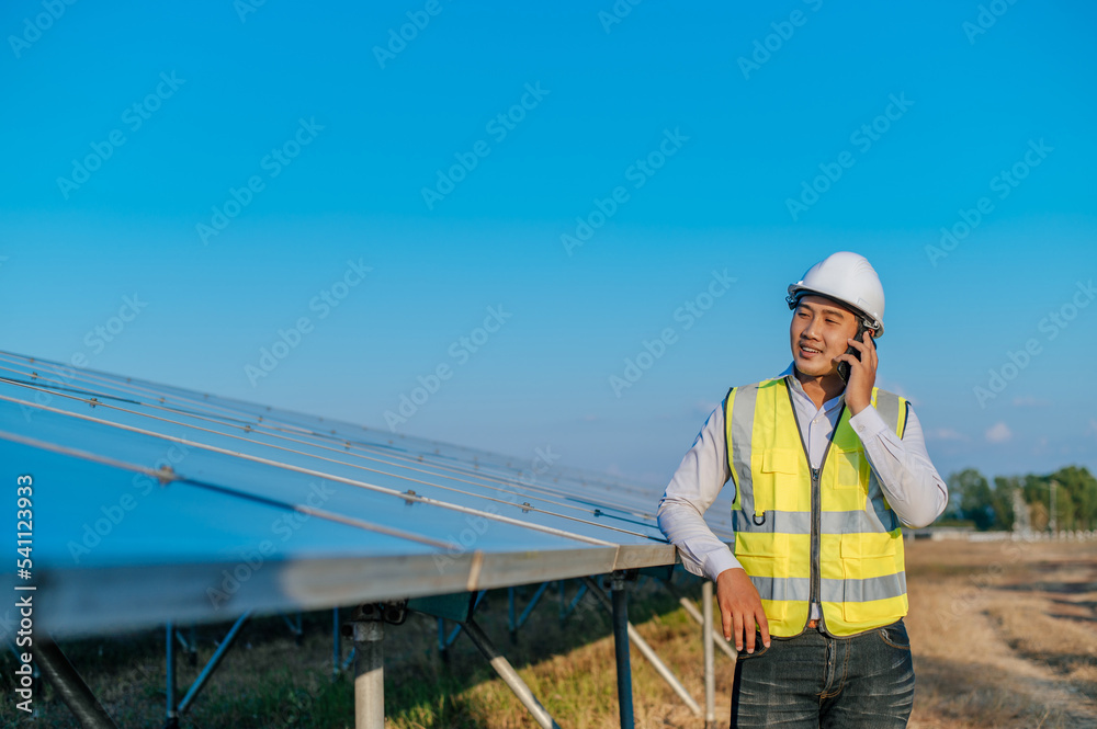 Young engineer use smartphone while working at solar farm Young engineer use smartphone while working at solar farm