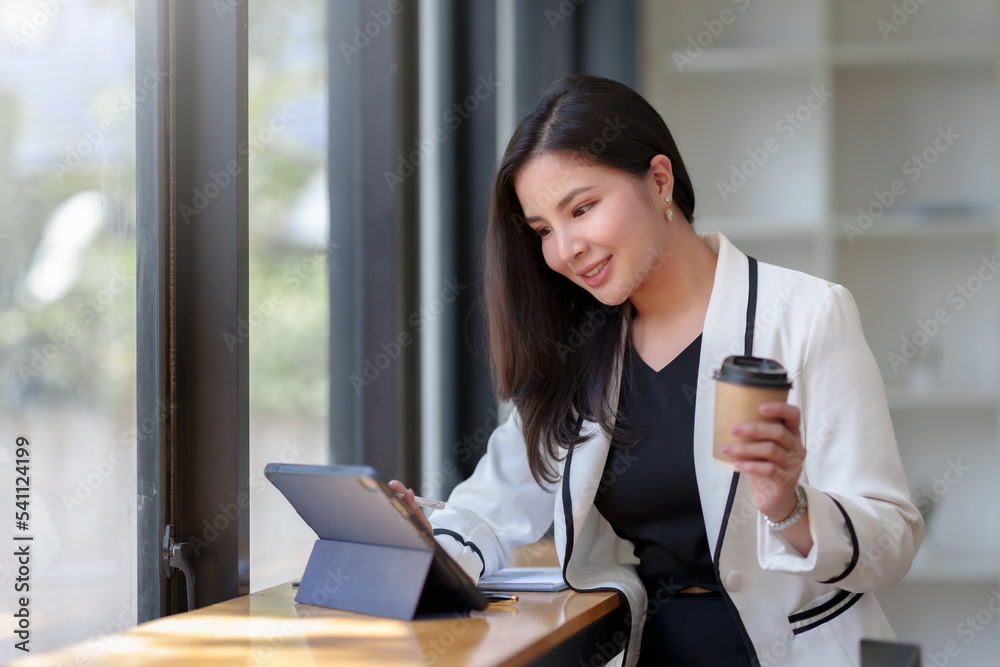 Cute and attractive Asian woman using tablet to work in a coffee shop happily and comfortably. Cute and attractive Asian woman using tablet to work in a coffee shop happily and comfortably.