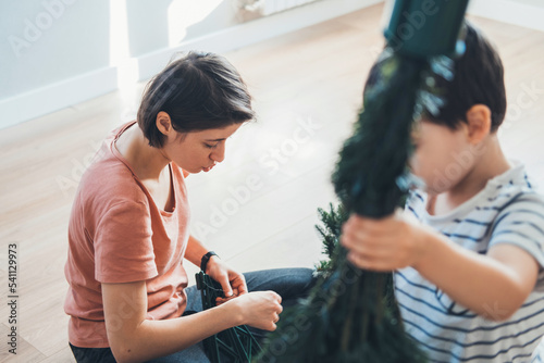 Mother and son unpacking the new artificial Christmas tree to assemble it. Happy family, childhood. People lifestyle.