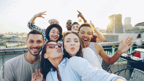 Point of view shot of happy friends taking selfe on roof at summer party laughing, posing and enjoying good company. Happiness, leisure and modern technology concept.