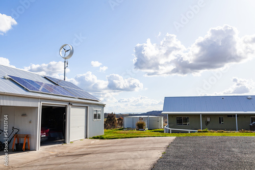 sustainable off grid living with solar power and wind turbine on roof beside farm house photo