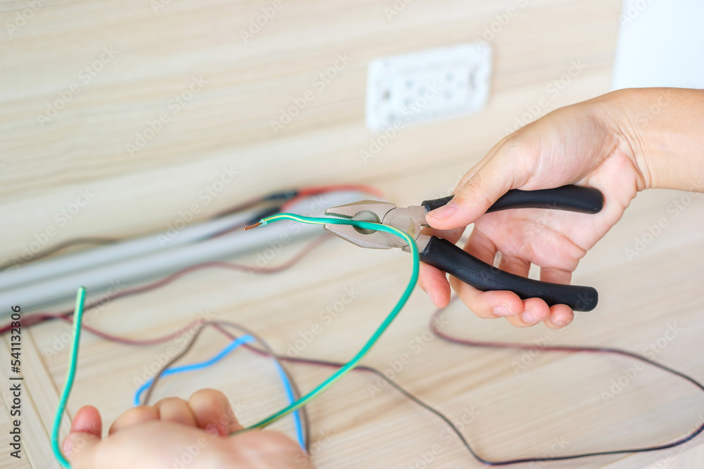 Electrician cuts electrical wires with pliers, Wiring cables installation for socket plug. Fixing, Renovation, Repair, service and development of home and apartment concepts Electrician cuts electrical wires with pliers, Wiring cables installation for socket plug. Fixing, Renovation, Repair, service and development of home and apartment concepts