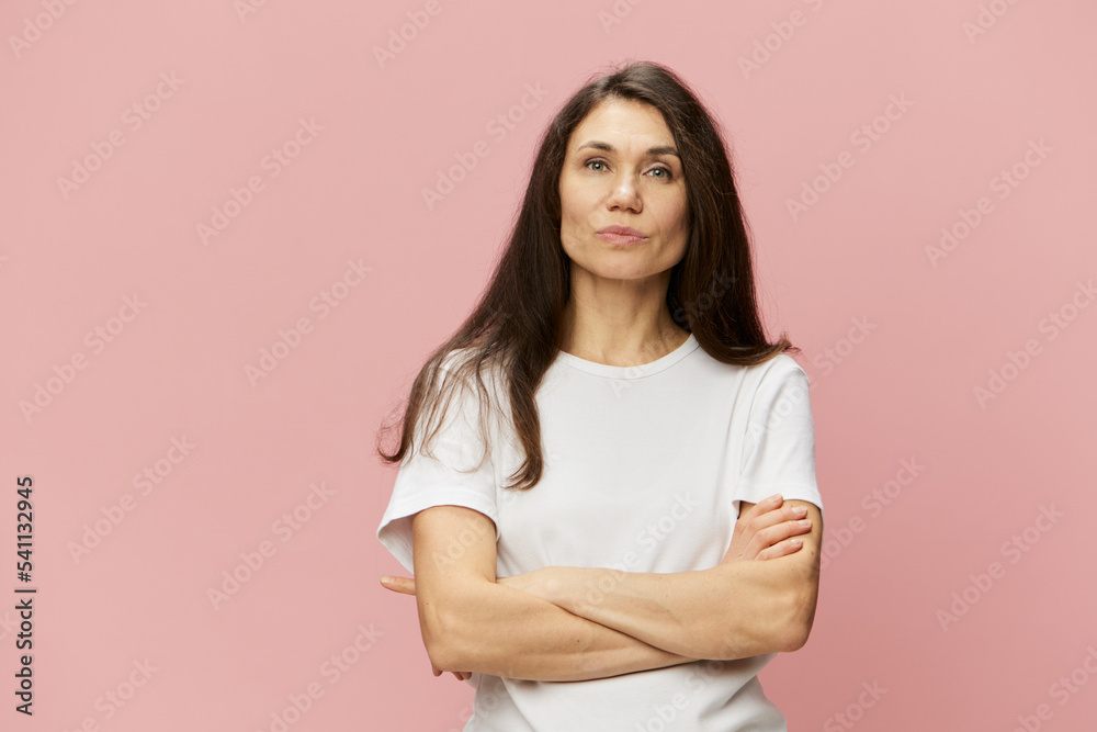 horizontal portrait on a pink background of a happy woman with her arms crossed on her chest in a white cotton T-shirt horizontal portrait on a pink background of a happy woman with her arms crossed on her chest in a white cotton T-shirt