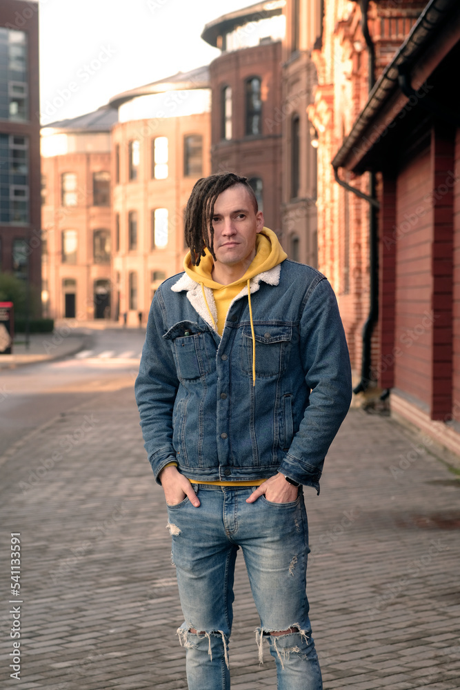 Handsome man with dreadlocks posing on city street. Positive male looking away, smiling. Handsome man with dreadlocks posing on city street. Positive male looking away, smiling.