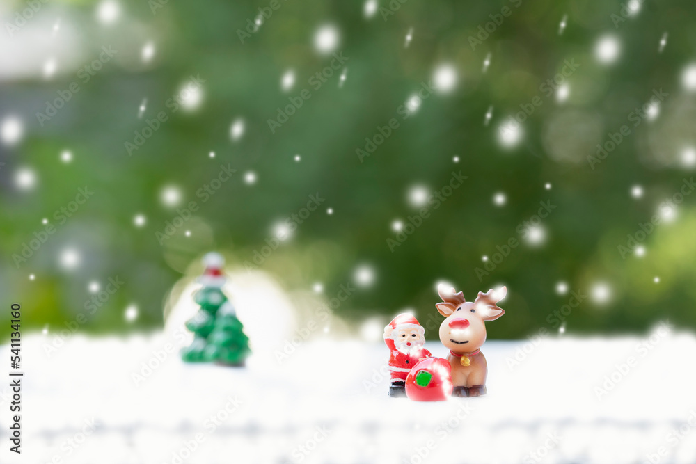 santa doll, reindeer and presents with snow decorated  background green nature. concept christmas celebration, santa claus deliver presents on snowy day
