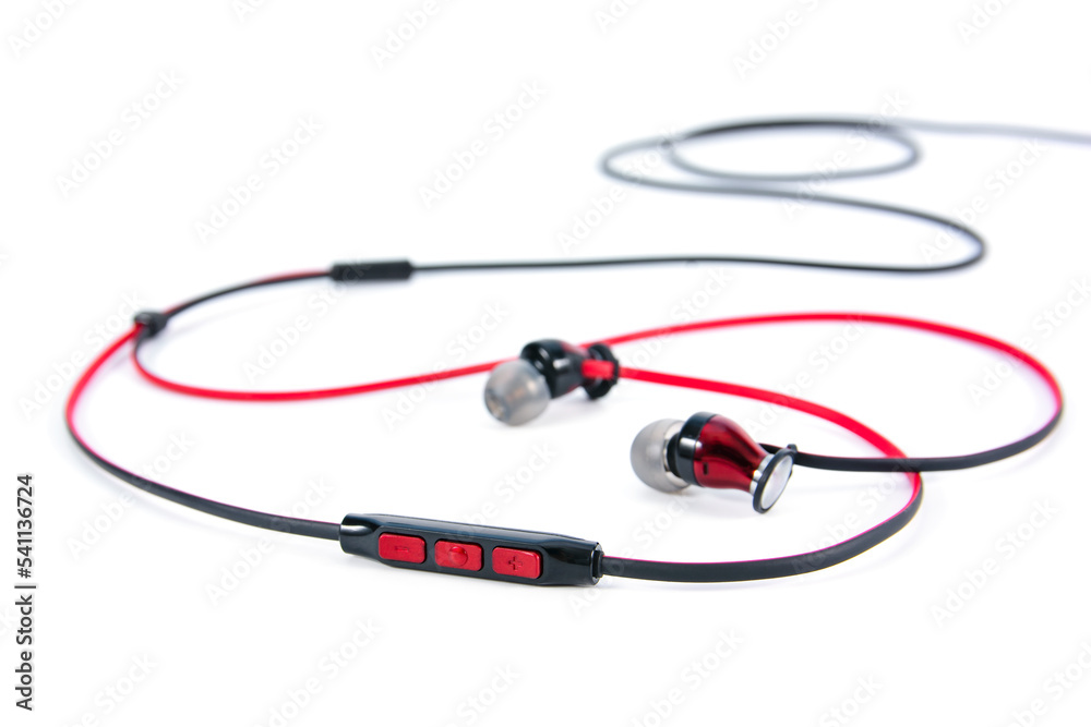 In ear headphones speaker button control isolated on white background. Closeup red and black wire in-ear headphones speaker button volume control isolated. In ear headphones speaker button control isolated on white background. Closeup red and black wire in-ear headphones speaker button volume control isolated.
