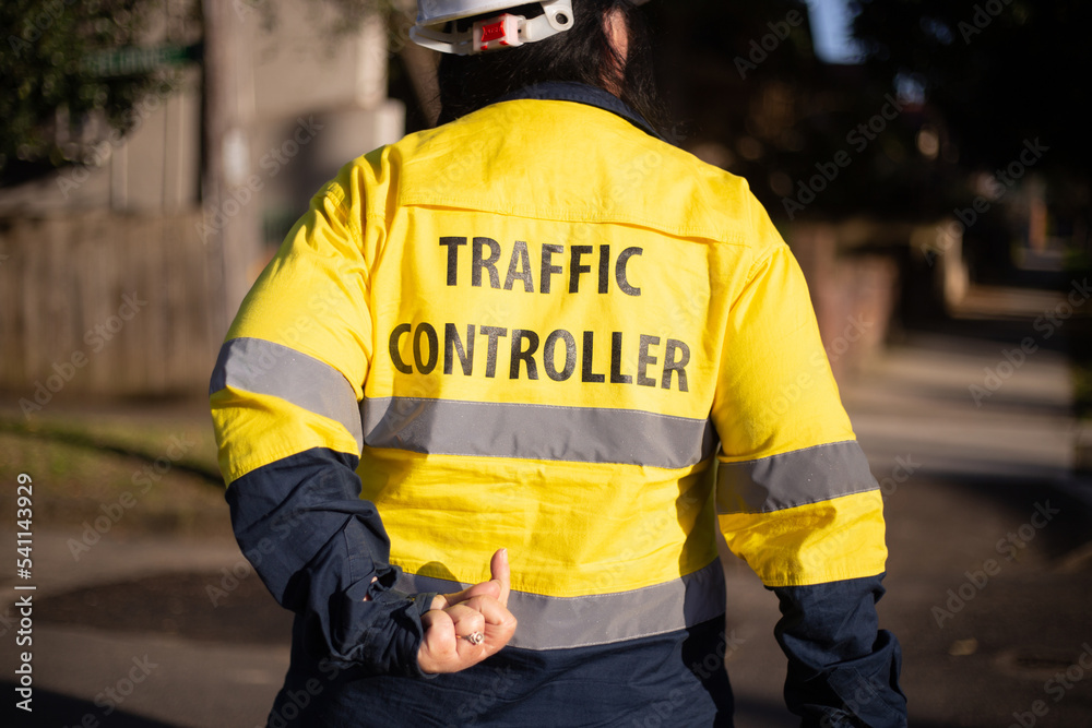 Back shot of a traffic controller wearing yellow jacket with silver reflectors Back shot of a traffic controller wearing yellow jacket with silver reflectors