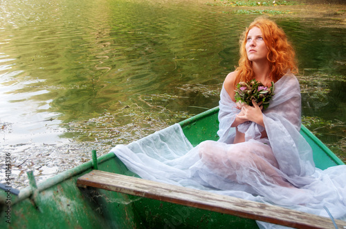 beautiful longing young sexy woman, redhead with red hair, bride, with a bouquet of flowers in a boat