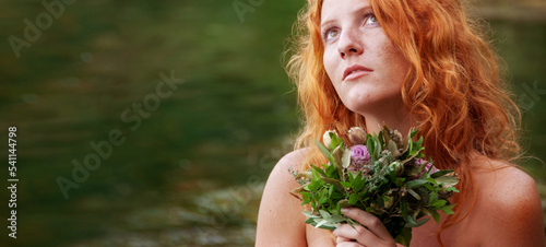 Fototapeta Naklejka Na Ścianę i Meble -  wide banner panorama portrait of beautiful young sexy redhead girl with longing questioning, asking, suffering look, with a bouquet of flowers, in front of green water background