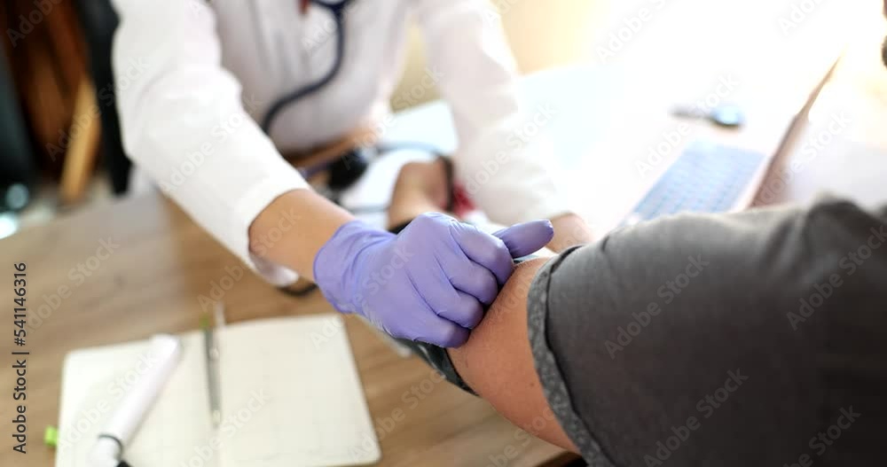 Doctor puts tonometer on patient arm and measures patient pressure during medical examination Doctor puts tonometer on patient arm and measures patient pressure during medical examination