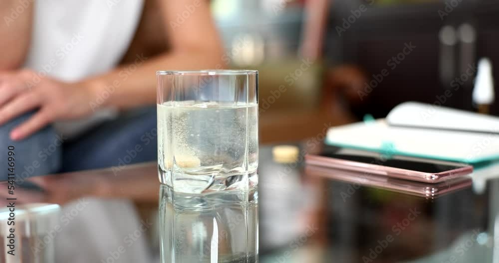 Pills dissolve in water with bubbles. Person sits on couch Pills dissolve in water with bubbles. Person sits on couch