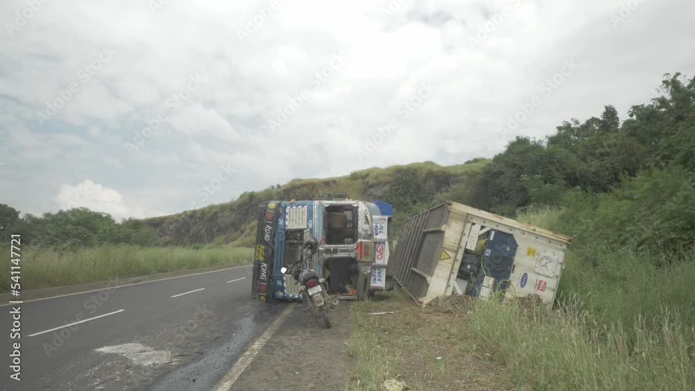 A lorry truck carrying a cold storage container toppled in an accident due to oversteering on a downhill ghat section on an Indian highway in 4k slow motion A lorry truck carrying a cold storage container toppled in an accident due to oversteering on a downhill ghat section on an Indian highway in 4k slow motion