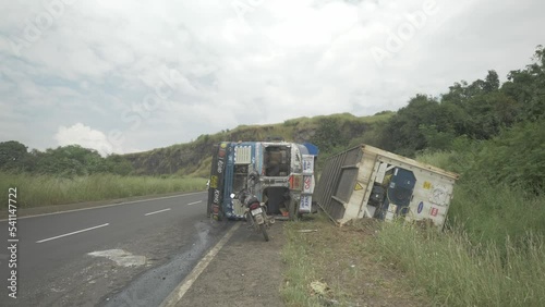 A lorry truck carrying a cold storage container toppled in an accident due to oversteering on a downhill ghat section on an Indian highway in 4k slow motion photo