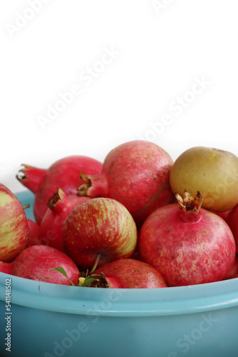 Many ripe red Pomegranate fruits in plastic bowl against white background. Punica granatum harvest 