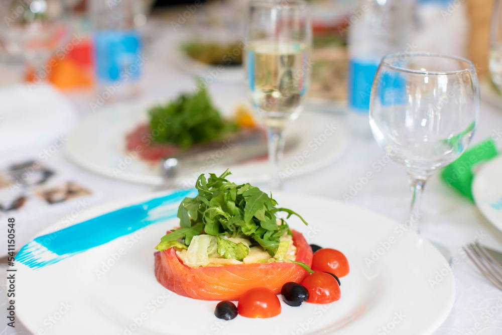 Close-up of a piece of red fish garnished with arugula on a plate in a restaurant.