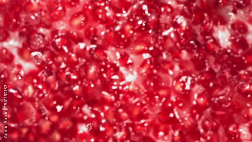 Pomegranate seeds falling on water surface with pomegranate seeds. Slow Motion.