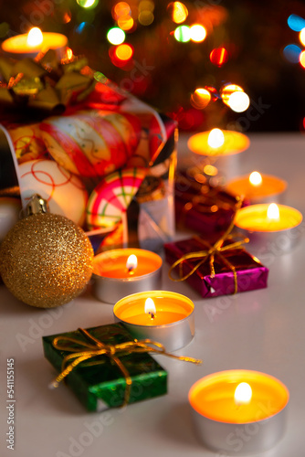 Christmas and New Year composition: burning candles and gift boxes, shallow depth of field, vertical