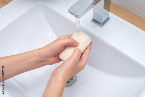 Children's hands with soap under the running water in the washbasin