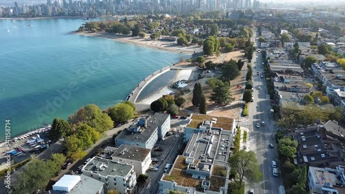 Drone shot of Kitsilano in Vancouver, British Columbia showing residential homes, condo apartment, beach, city skyline, cars on streets, ocean, ships and trees. photo