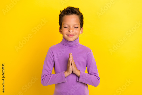 Photo portrait of charming little boy closed eyes hands pray gesture make wish wear trendy violet look isolated on yellow color background photo