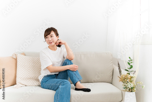 家のソファでリラックスするデニム姿の日本人女性 
