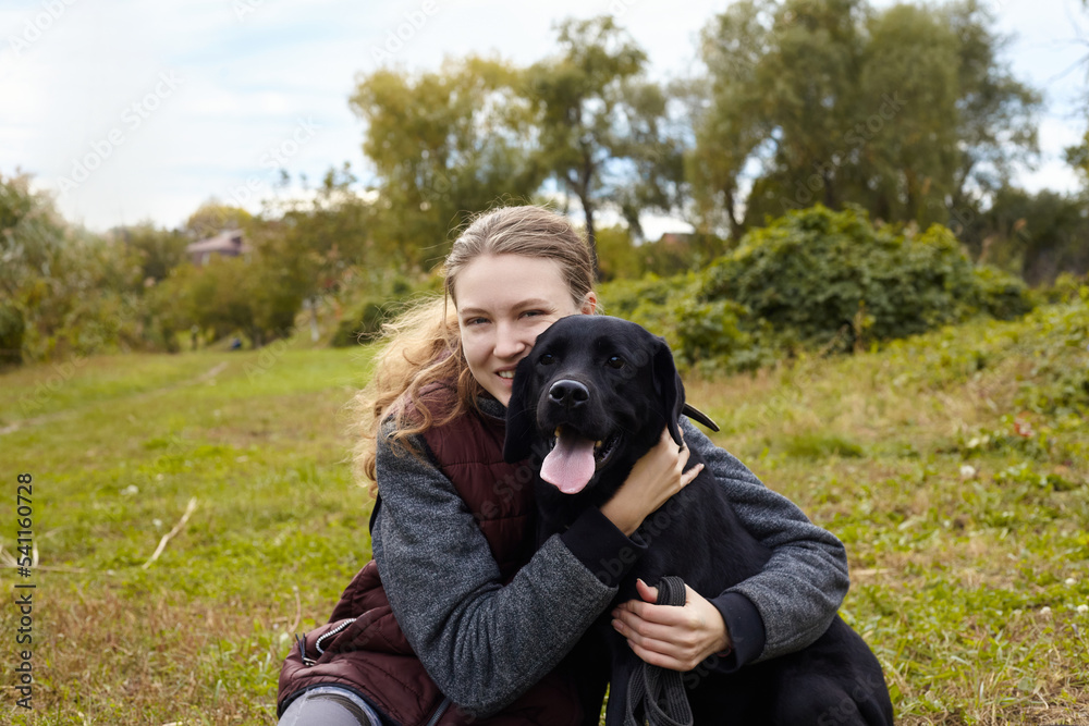 a joyful woman is sitting on the grass with her Labrador retriever dog and enjoying an autumn vacation
a joyful woman is sitting on the grass with her Labrador retriever dog and enjoying an autumn vacation