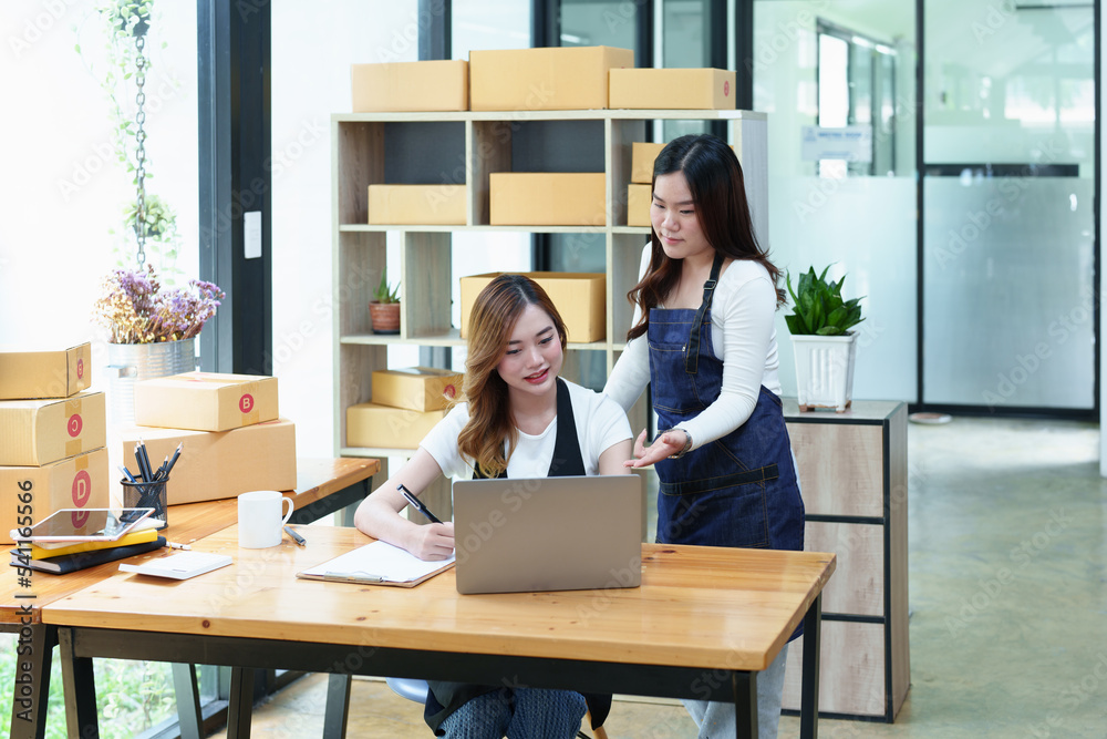 Starting small business two entrepreneur of independent Asian woman smiling using computer laptop with cheerful success of online marketing package box items and SME delivery concept Starting small business two entrepreneur of independent Asian woman smiling using computer laptop with cheerful success of online marketing package box items and SME delivery concept