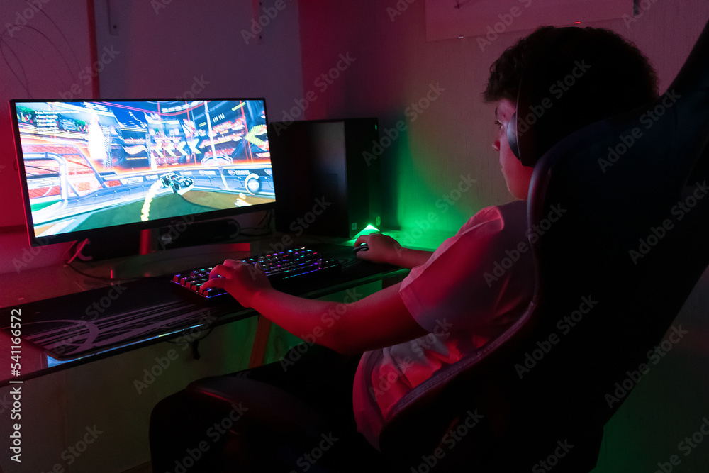 young person playing on the computer using the keyboard, dimmed lights ...