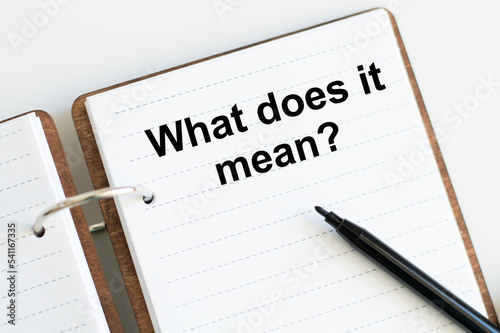 text what does it mean written on notepad with penciland white background. High quality photo