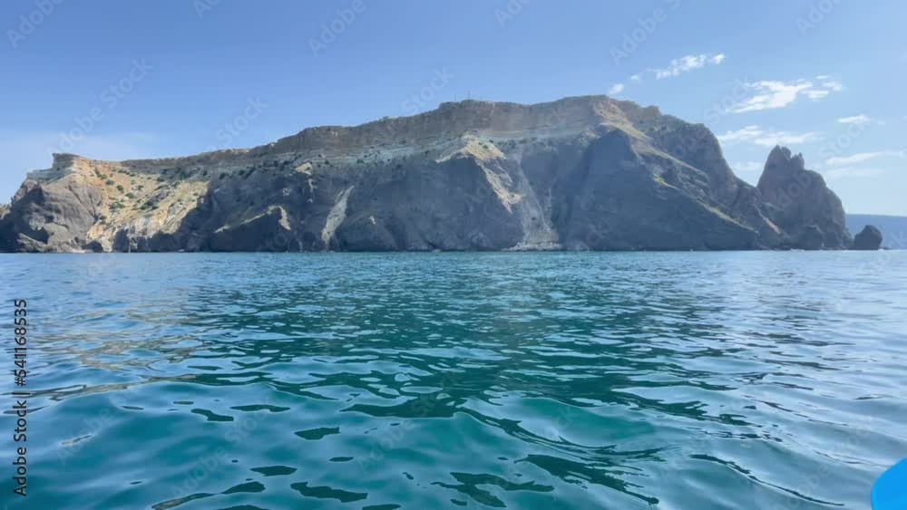 In kayak sportsman, kayakers rowing at calm clear blue sea on calm summer day with no waves against the backdrop of coastal cliffs. The concept of an active and healthy life in harmony with nature. In kayak sportsman, kayakers rowing at calm clear blue sea on calm summer day with no waves against the backdrop of coastal cliffs. The concept of an active and healthy life in harmony with nature.