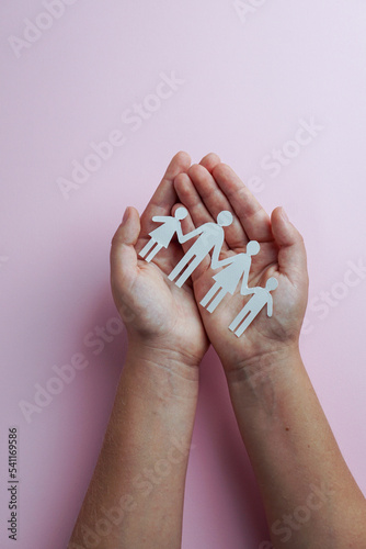 hands holding paper family cutout, life health insurance, social distancing concept, covid19, on the rose color background, family protection