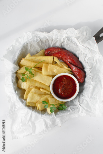 slices of fried yam, sausage and sauce, slices fried yam and stew on parchment paper, Nigerian fried yam photo