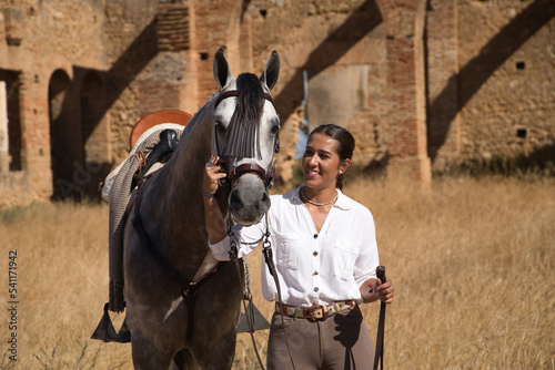 Young and beautiful woman with her horse, resting with him, caressing him, happy in the countryside. Concept horse riding, animals, dressage, horsewoman, care, love.