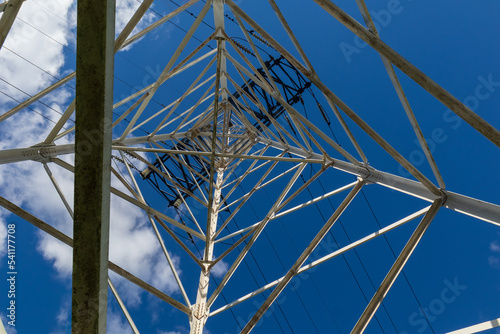 A high-voltage power transmission line. Power line support against a blue sky, bottom view