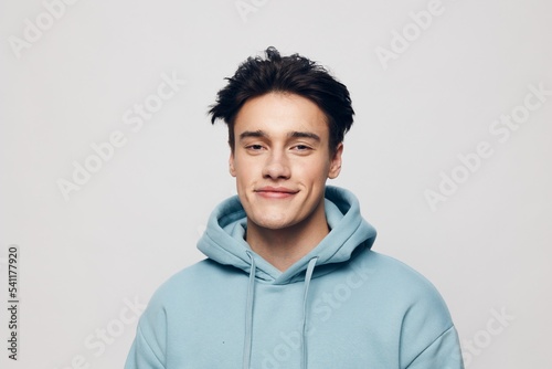 horizontal portrait of a pleasantly smiling young man in a light hoodie looking into the camera