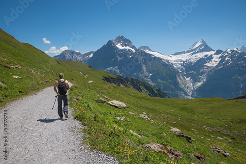hiker at mountain trail Grindelwald First, stunning view to Bernese Alps and glacier