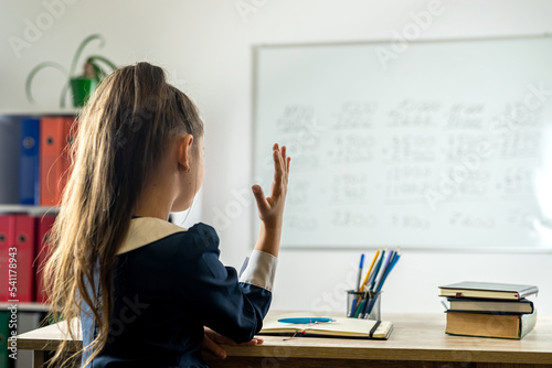 elementary school student raises her hand because she is ready answer the teacher's question