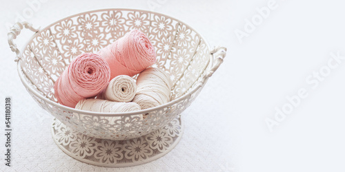 Handmade macrame braiding and cotton threads in basket on white background. Good image for macrame and handicrafts banners and advertisement. Copy space