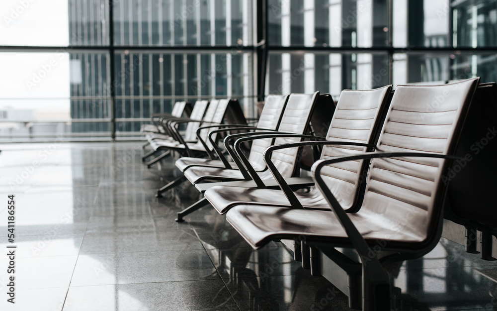 International airport lounge. Side view of row of seating chairs on window background, selective focus