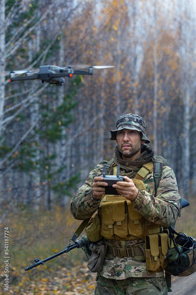 The mercenary launches a reconnaissance drone in a forest. Vertical photo.