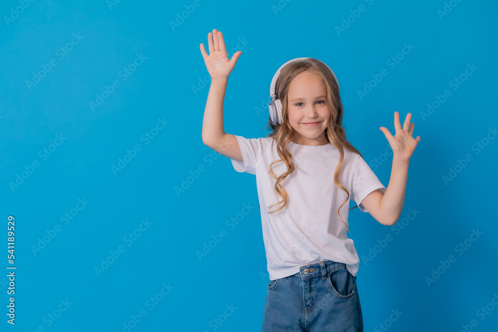 blonde girl in jeans and a white T-shirt listens to music with headphones and dances blonde girl in jeans and a white T-shirt listens to music with headphones and dances