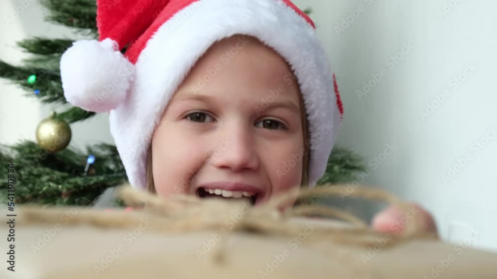 Happy child girl receiving Christmas gift box on background of Christmas tree close up. Child accepting present from parents. Holidays, childhood, children dreams and celebration Happy child girl receiving Christmas gift box on background of Christmas tree close up. Child accepting present from parents. Holidays, childhood, children dreams and celebration