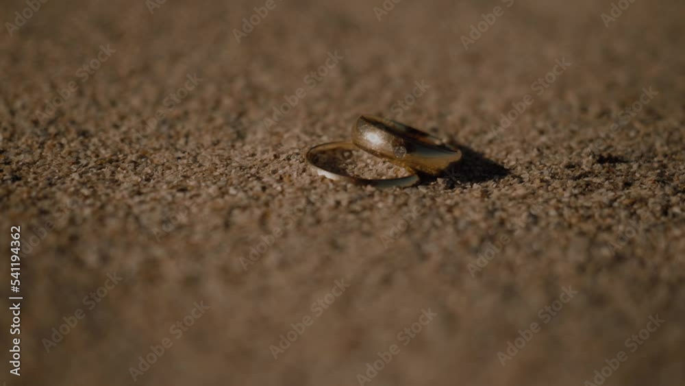 Close up shot wedding rings being covered with sand particles on a windy sunny day at the beach Close up shot wedding rings being covered with sand particles on a windy sunny day at the beach